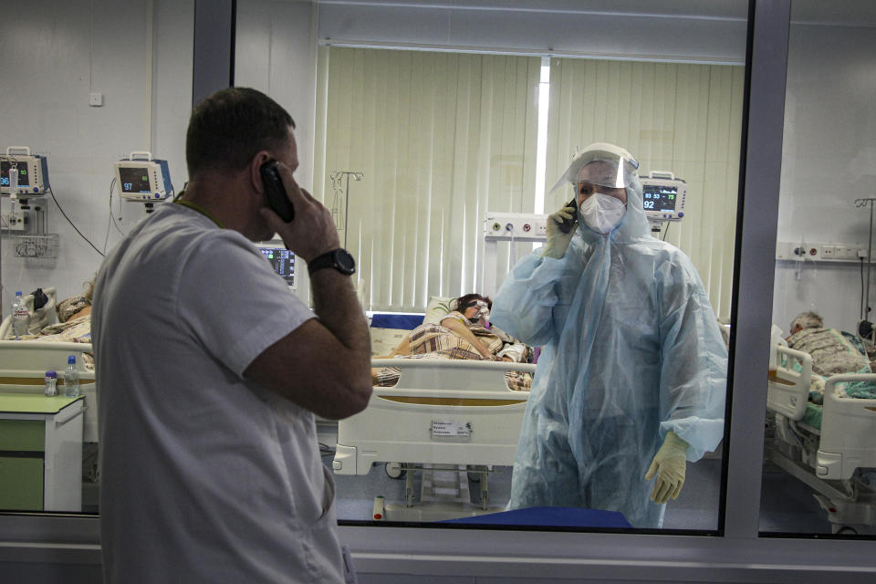 Medical staff members talk to each other on the phone as one of them treats patients with coronavirus at an ICU in Infectious Hospital No. 23 in Nizhny Novgorod, Russia, on Wednesday, Oct. 20, 2021. The low vaccination rate in Russia, where only about a third of the population is fully vaccinated, is causing concern as the country suffers a sharp rise in cases, setting records for infections and deaths nearly every day this month. (AP Photo/Roman Yarovitcyn)