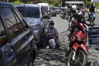 Drivers and motorcyclists wait their turn to fill up at a gas station in Cali, Colombia, Friday, May 7, 2021. Protesters are blocking the main roads as a part of anti-government protests that has resulted in cities having a shortage of food and fuel. (AP Photo/Andres Gonzalez)