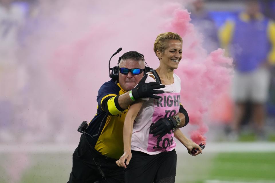 A protester is brought down by a security guard after she runs onto the field.