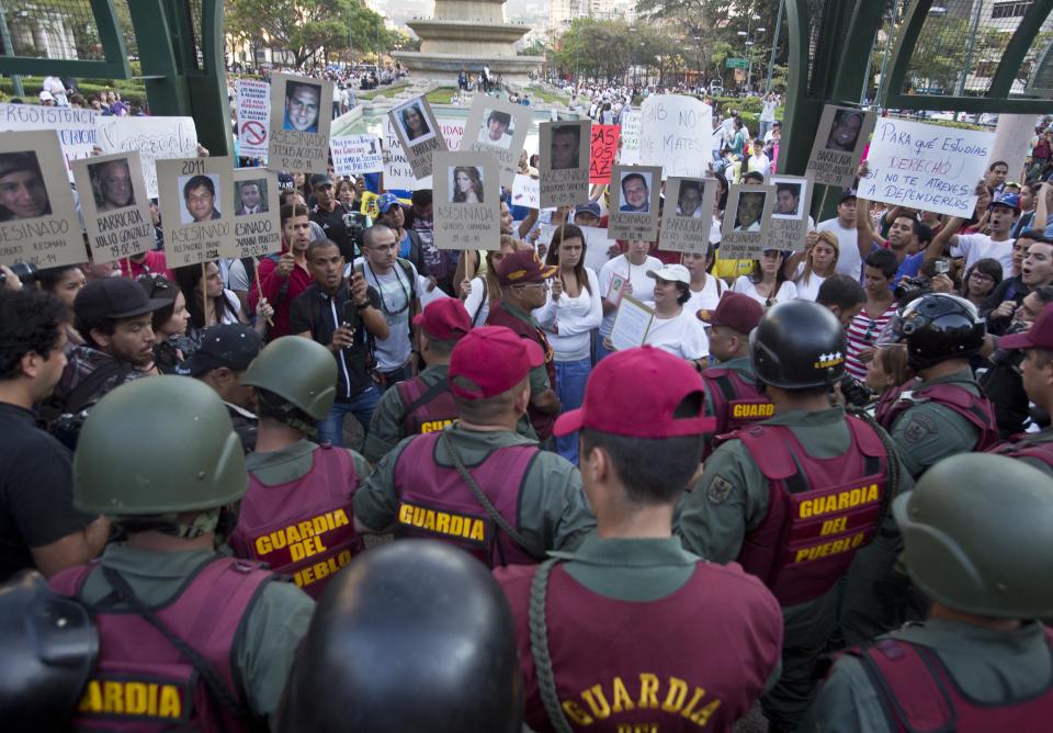 Demonstrators holds cardboard posters showing images the demonstrators killed during anti-government protests inside Plaza Altamira in Caracas, Venezuela, Tuesday, March 18, 2014. The posters have the the date of death, the name of a dead demonstrator and the word "Assasinated" written in Spanish. Protesters blocked the streets only when traffic lights turned red under the watchful gaze of the National Guard. Security forces have taken control of the plaza that has been at the heart of anti-government protests that have shaken Venezuela for a month. (AP Photo/Esteban Felix)