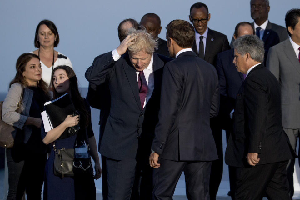 British Prime Minister Boris Johnson, center left, and French President Emmanuel Macron, center right, arrive for the G-7 family photo at the G-7 summit at the Hotel du Palais in Biarritz, France, Sunday, Aug. 25, 2019. (AP Photo/Andrew Harnik)