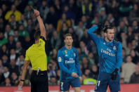 Soccer Football - La Liga Santander - Real Betis vs Real Madrid - Estadio Benito Villamarin, Seville, Spain - February 18, 2018 Real Madrid’s Gareth Bale is shown a yellow card by referee Jesus Gil Manzano as Cristiano Ronaldo looks on REUTERS/Jon Nazca