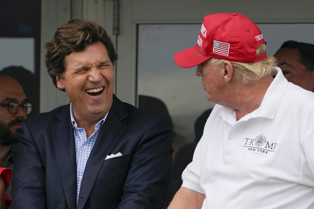 FILE - Tucker Carlson, left, and former President Donald Trump, right, react during the final round of the Bedminster Invitational LIV Golf tournament in Bedminster, N.J., July 31, 2022. Documents in defamation lawsuit illustrate pressures faced by Fox News journalists in the weeks after the 2020 presidential election. The network was on a collision course between giving its conservative audience what it wanted and reporting uncomfortable truths about then-President Donald Trump and his false fraud claims.(AP Photo/Seth Wenig, File)