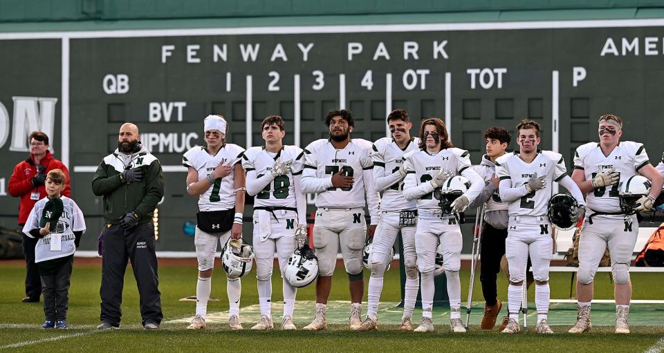 The Nipmuc Regional football team stands for the national anthem before a Thanksgiving Eve game against cross-street rival Blackstone Valley Tech at Fenway Park, Nov. 24, 2021.