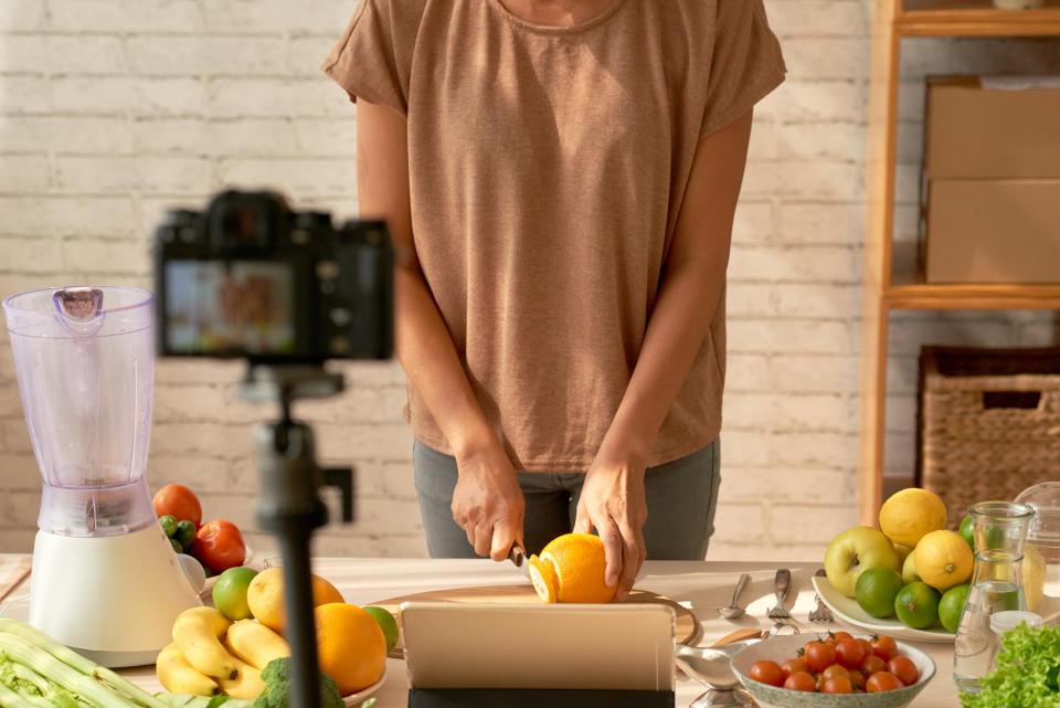 Cropped image of food blogger cutting fresh orange for morning smoothie