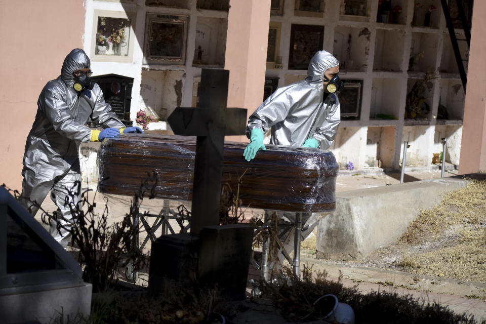 A coffin holding the remains of Cristobal Huanca Mendoza is guided by workers through a cemetery to a common grave area, in Cochabamba, Bolivia, Thursday, July 2, 2020. The coffin of Mendoza, who died Sunday in Cochabamba, is wrapped in plastic as is common by funeral homes when working with COVID-19 victims or suspected victims of the new coronavirus. (AP Photo/Dico Soliz)