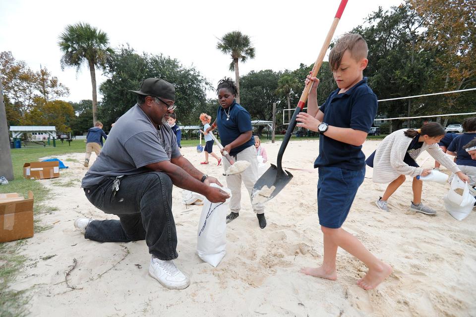 Students from Tybee Island Maritime Academy fill a sand bag for Marvin Sims Wednesday at Memorial Park on Tybee Island. The students were helping out during their PE time as residents collected sand bags ahead of the potential for flooding from the remnants of Hurricane Ian.