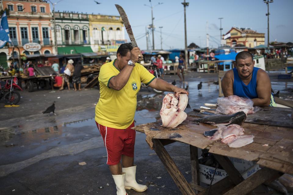 In this Sept. 7, 2019 photo, a vendor prepares fish for customers at his street stand at the Ver-o-Peso riverside market in Belém, Brazil. The Ver-o-Peso open-air market is the icon of a city that was once known for the rubber trade but that is now best known as the Amazon's culinary capital. (AP Photo/Rodrigo Abd)