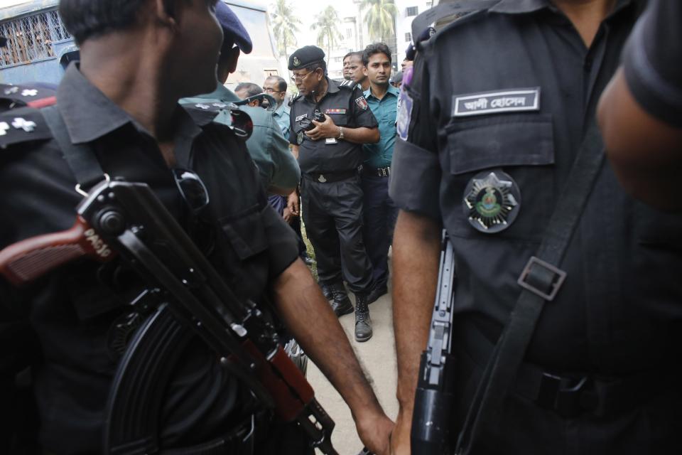 Members of Bangladesh's Rapid Action Battalion (RAB) stand guard with police outside a courthouse as the verdict for a 2009 mutiny is announced, in Dhaka