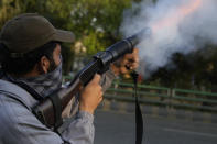 A police officer fires tear gas shell to disperse the supporters of Pakistan's former Prime Minister Imran Khan during clashes, in Lahore, Pakistan, Wednesday, March 8, 2023. Pakistani police used water cannons and fired tear gas to disperse supporters of the country's former Prime Minister Khan Wednesday in the eastern city of Lahore. Two dozen Khan supporters were arrested for defying a government ban on holding rallies, police said. (AP Photo/K.M. Chaudary)