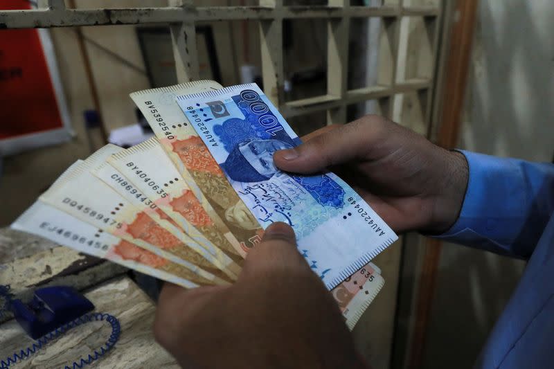 A man counts Pakistani rupee notes at a currency exchange shop in Peshawar