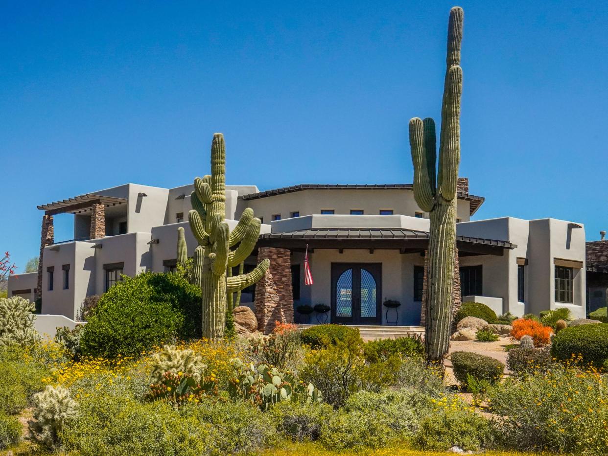 An adobe mansion with cacti out front and blue skies in the background in Scottsdale