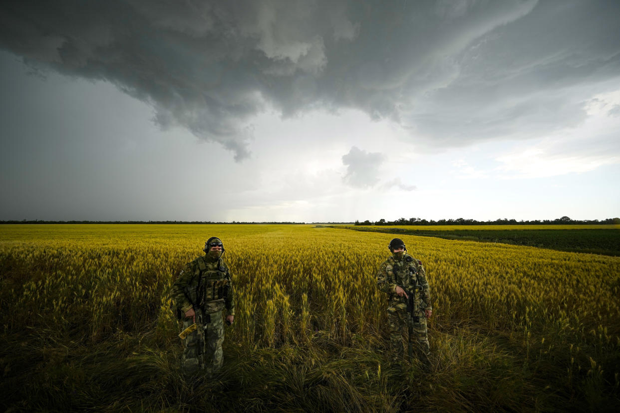 FILE - Russian soldiers guard an area next to a field of wheat as foreign journalists work in the Zaporizhzhia region in an area under Russian military control, southeastern Ukraine, Tuesday, June 14, 2022. Despite getting bogged down in Ukraine, the Kremlin has resisted announcing a full-blown mobilization, a move that could prove to be very unpopular for President Vladimir Putin. That has led instead to a covert recruitment effort that includes trying to get prisoners to make up for the manpower shortage. This photo was taken during a trip organized by the Russian Ministry of Defense. (AP Photo, File)