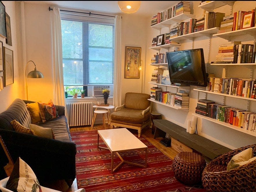 Eclectic living room with red rug, dark-colored sofa, and angled TV among bookshelves