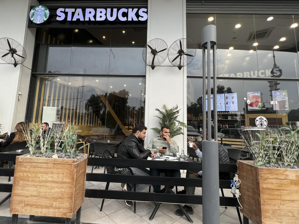 People sit in an unlicensed Starbucks cafe in Baghdad, Iraq, Wednesday, Dec. 21, 2022. Real Starbucks merchandise is imported from neighboring countries to stock the three cafes in the city, but all are unlicensed. Starbucks filed a lawsuit in an attempt to shut down the trademark violation but the case was shuttered after the owner allegedly threatened lawyers hired by the coffee house. (AP Photo/Ali Abdul Hassan)