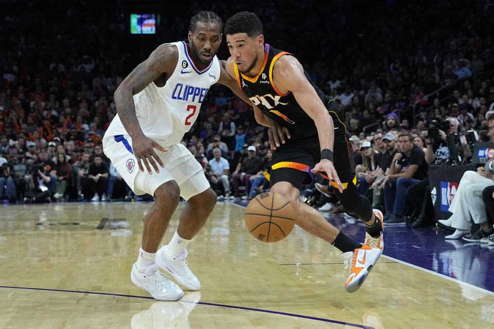 Phoenix Suns guard Devin Booker (1) drives on Los Angeles Clippers forward Kawhi Leonard (2) during the second half of Game 2 of a first-round NBA basketball playoff series, Tuesday, April 18, 2023, in Phoenix. (AP Photo/Matt York)