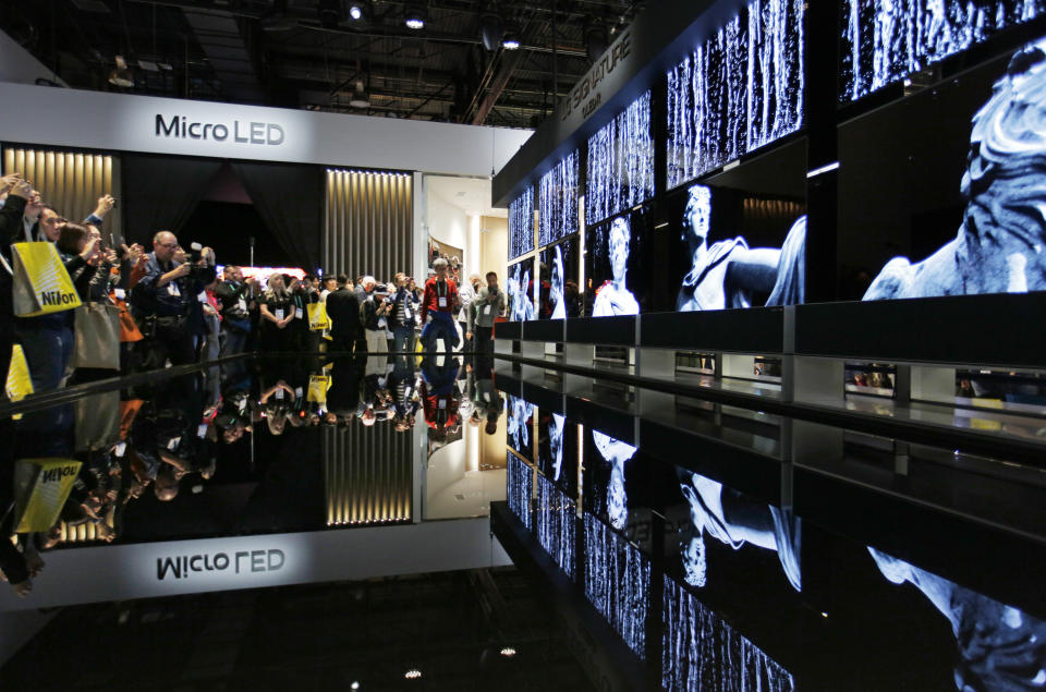 People take pictures of a display of LG Signature OLED R TVs at the LG booth during the CES tech show, Tuesday, Jan. 7, 2020, in Las Vegas. (AP Photo/John Locher)