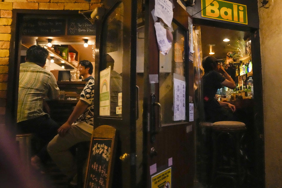 People gather at bars after government imposed 8 p.m. closing time for restaurants and bars under Tokyo's fourth state of emergency Saturday, July 17, 2021, in Tokyo. The latest state of emergency has asked restaurants and bars to close by 8 p.m., if not entirely. This has pushed people to drink outside, although many bars remain open and bustling with customers who are defying the rules and expressing frustration and indifference. (AP Photo/Kiichiro Sato)