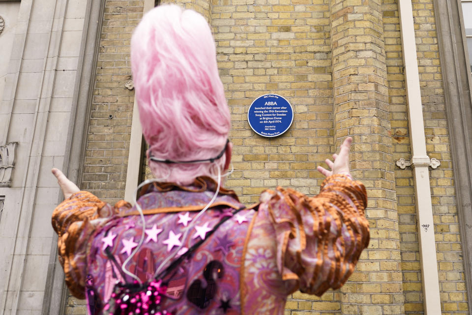 A man gestures to the ABBA blue plaque as people take part in a silent disco event to celebrate the 50th year anniversary since ABBA won the Eurovision Song contest, outside the Brighton Dome, in Brighton, England, Saturday, April 6, 2024. Fans are celebrating 50 years since ABBA won its first big battle with “Waterloo.” A half century ago on Saturday, April 6, the Swedish quartet triumphed at the 1974 Eurovision Song Contest with the peppy love song. (AP Photo/Alberto Pezzali)