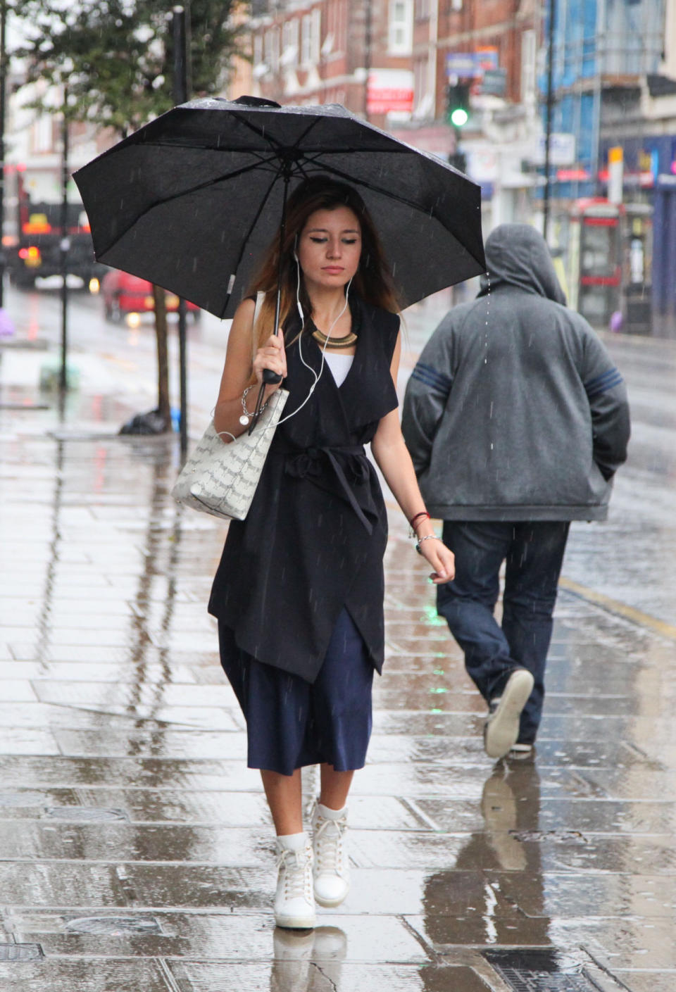 Wet Wimbledon. Woman under an umbrella walks in the famous London suburb (Rex)