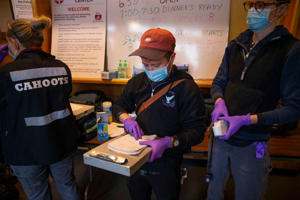 Ve Gulbrandsen, center, an EMT with CAHOOTS, joins a team from White Bird in screening guests for health concerns at the Egan Warming Center in Springfield, Ore. on March 16, 2020. | Chris Pietsch—The Register-Guard/USA Today/Sipa