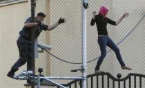 A policeman chases a supporter of the female punk band "Pussy Riot" jailed members while climbing on a fence enclosing the Turkish embassy near a court building in Moscow, August 17, 2012.