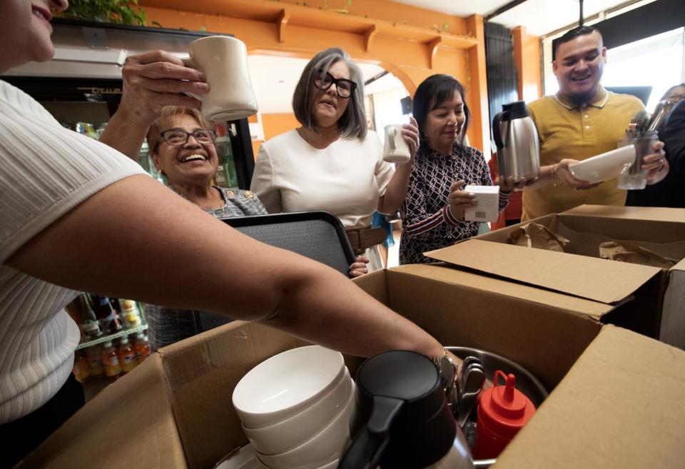 Maria Flores, left, owner of Pupuseria Cuzcatlan, holds up a coffee mug.