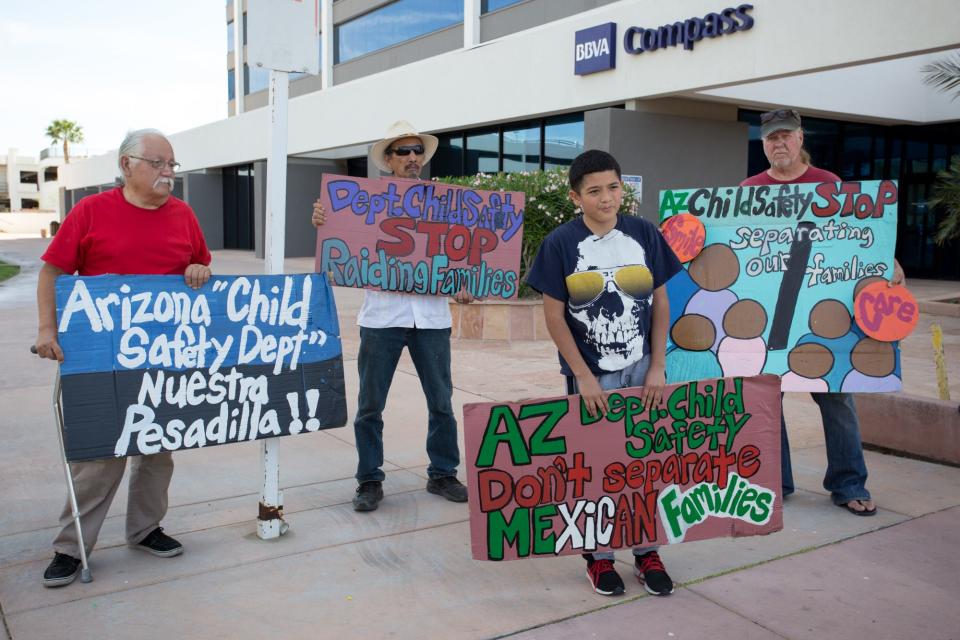 Christopher Garcia (second from right) speaks about his experiences with the Arizona Department of Child Safety while Salvador Reza, Tupac Enrique Acosta and Rob McElwain (from left to right) hold signs behind him during a protest against the agency outside of the agency's office on Monday, Mar. 21, 2016, in Phoenix.