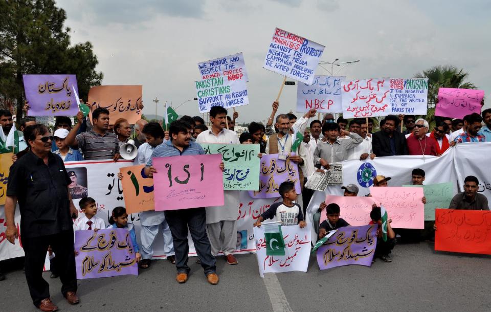 In this Friday, April 25, 2014 photo, representatives of trade and business unions carry pro-army signs during a rally to support the Pakistan army and its Inter-Services Intelligence wing in Islamabad, Pakistan. The mystery signs arrived in Pakistan as its powerful military faces off with the country’s largest private television station over allegations that its forces were behind a shooting that seriously wounded Hamid Mir, one of its top anchors. But behind the chanting demonstrations and garish loyalty posters lies the deep challenge confronting Pakistan: Where does power lie in this country that’s undergone three military coups since independence, with its army or its nascent civilian government? Placards in Urdu read, "we salute Pak army, we won't let Pak army down, long live army." (AP Photo/B.K. Bangash)