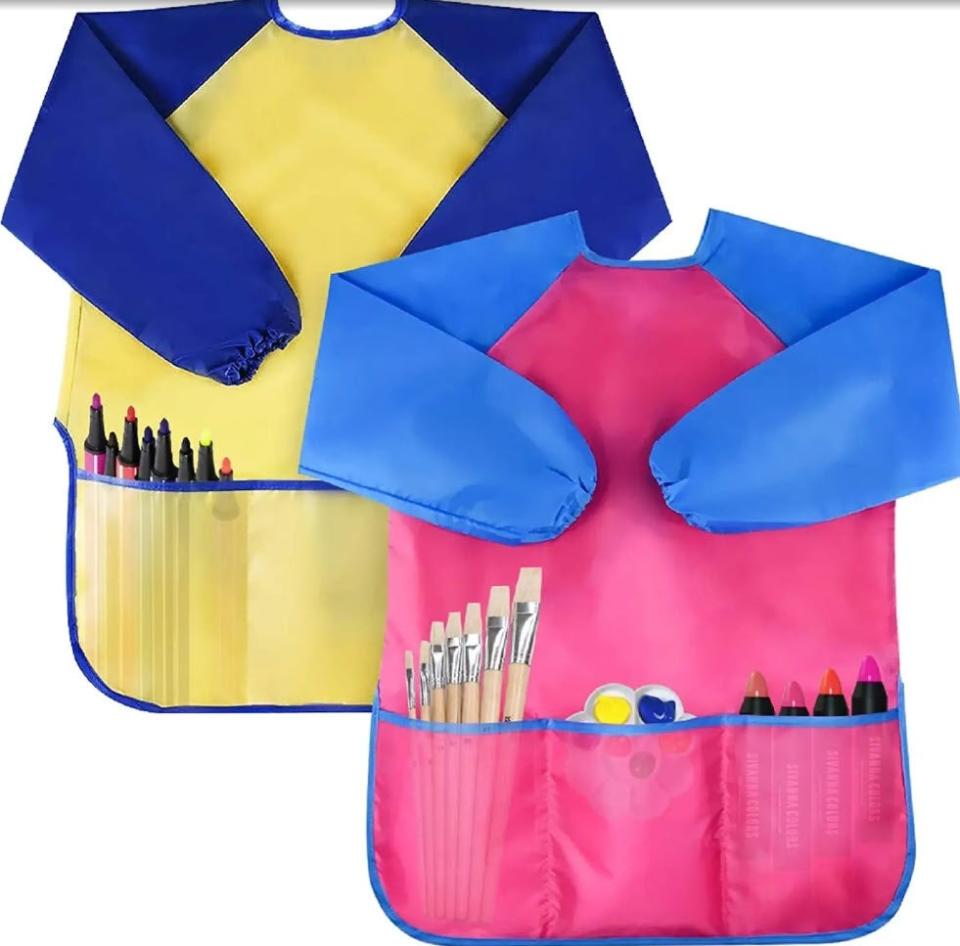 set of two painting apron styles with long sleeves and three pockets holding markers, paint and paintbrushes