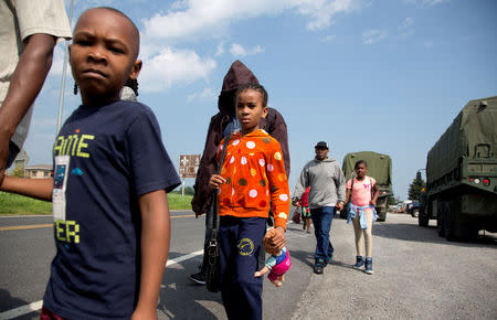 A group of asylum seekers walk down the street as they are escorted from their tent encampment to be processed at Canada Border Services in Lacolle, Quebec, Canada August 11, 2017. REUTERS/Christinne Muschi