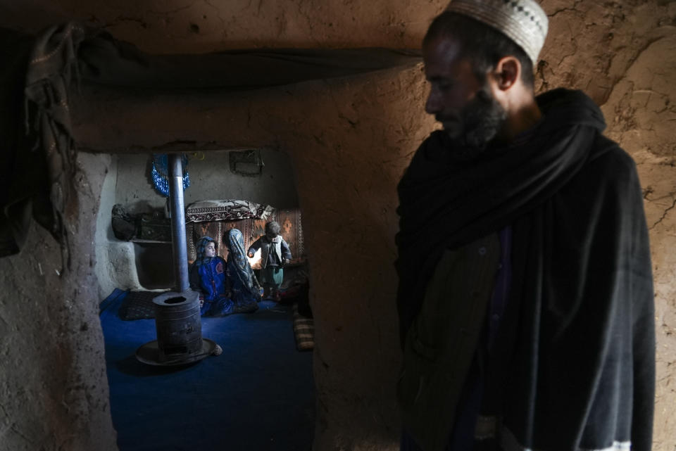 Hamid Abdullah stands outside the room where his children are playing at a settlement near Herat, Afghanistan, Dec. 16, 2021. Abdullah was selling his young daughters into arranged marriages, desperate for money to treat his chronically ill wife, pregnant with their fifth child. (AP Photo/Mstyslav Chernov)