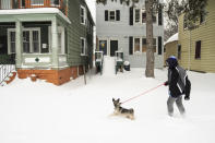 Alex Lane walks his dog, Niay, a German Shepherd mix, through the snow on the West Side, Saturday, Nov. 19, 2022 in Buffalo, N.Y. Residents of northern New York state are digging out from a dangerous lake-effect snowstorm that had dropped nearly 6 feet of snow in some areas and caused three deaths. The Buffalo metro area was hit hard, with some areas south of the city receiving more than 5 feet by early Saturday. (Libby March /The Buffalo News via AP)