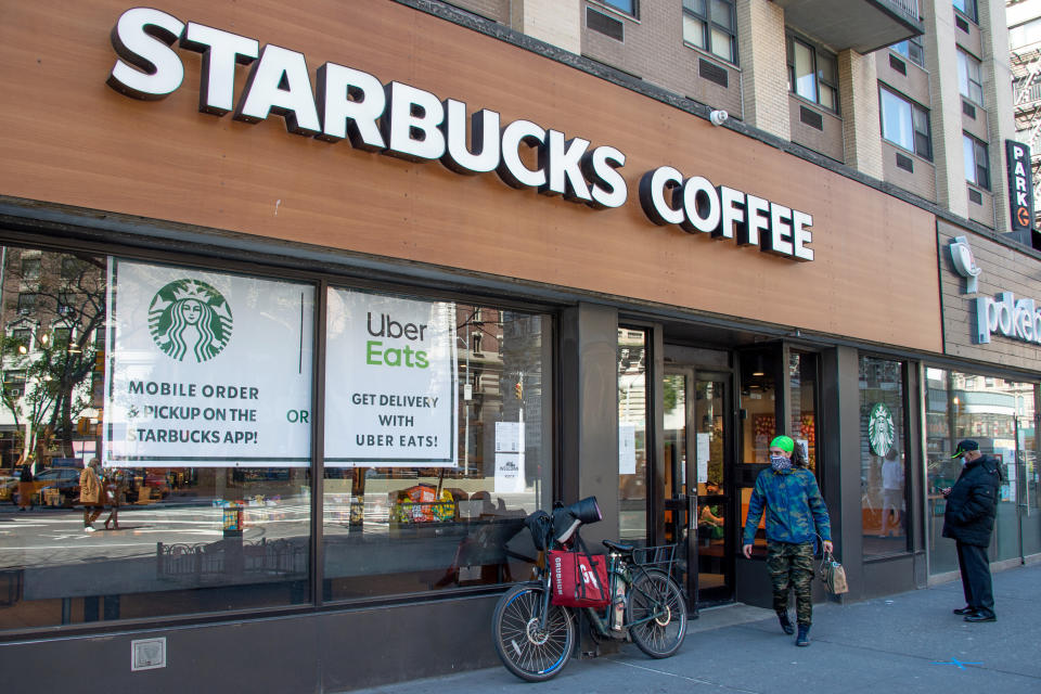 A delivery rider wearing a protective mask picks up an order from Starbucks on April 28 in New York City. Workers across the country are expected to head back to the stores as states reopen. (Photo: Alexi Rosenfeld via Getty Images)