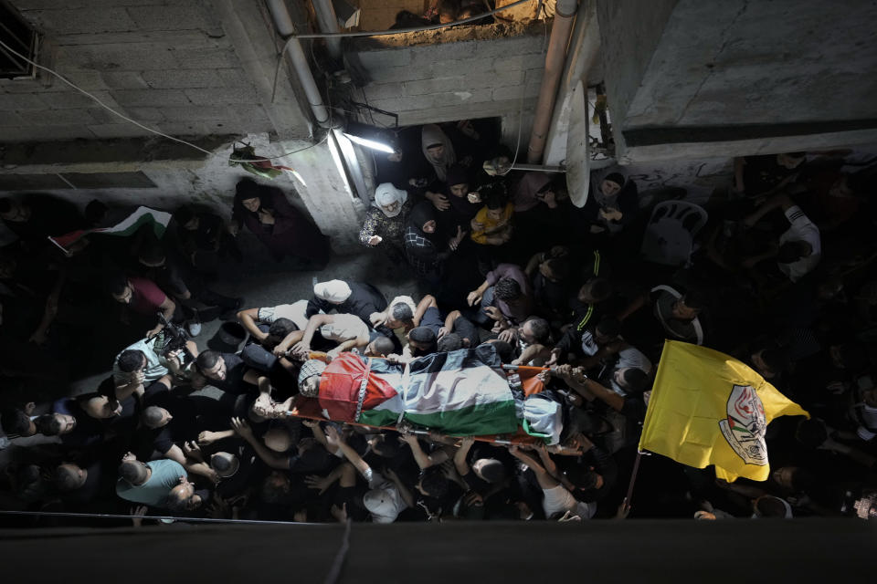 Mourners carry the body of Palestinian Alaa Zaghal during his funeral in Askar refugee camp near the West Bank city of Nablus, Wednesday, Oct. 5, 2022. Israeli troops have exchanged fire with Palestinians during an arrest raid in the occupied West Bank, killing Zaghal and forcing the surrender of another. The Israeli military identified the wanted man an activist in the Islamic militant group Hamas, and said he was suspected in a shooting attack on an Israeli bus and a taxi near Nablus earlier this week. Palestinian medics say at least seven people were wounded. (AP Photo/Majdi Mohammed)
