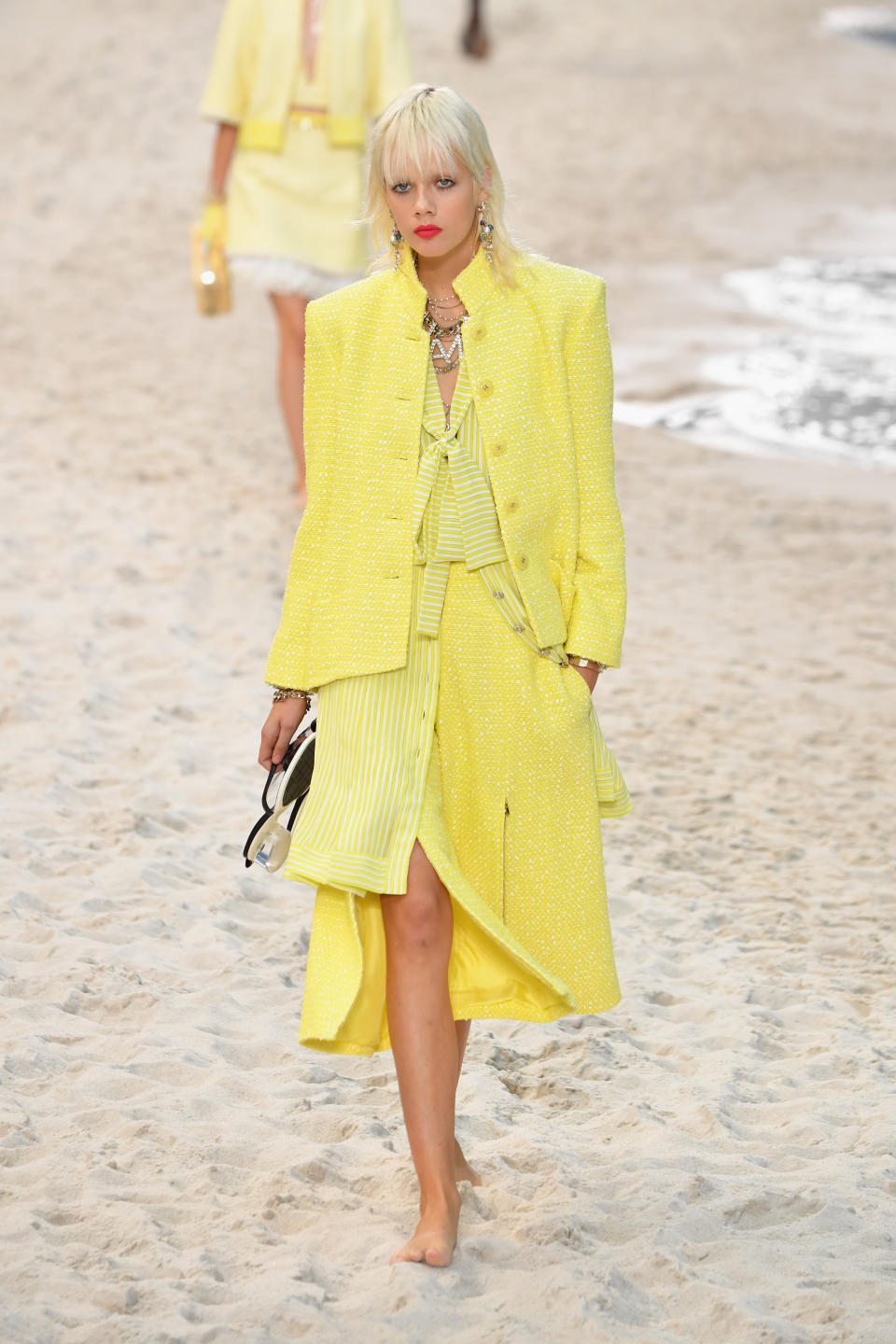 <p>Absolut sommertauglich ist auch dieser Look: Ein eleganter Materialmix in Zitronengelb mit dem für Chanel typischen Bordürensaum und einer farblich passenden Bouclé-Tweedjacke. (Bild: Getty Images) </p>