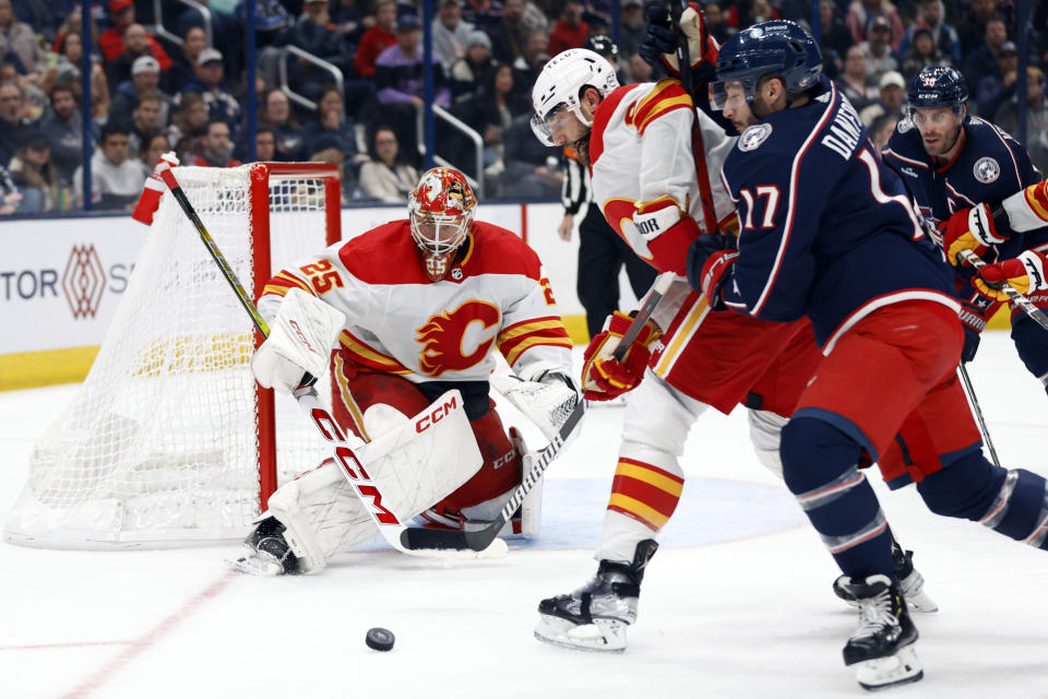 Calgary Flames goalie Jacob Markstrom, left, makes a stop in front of Flames defenseman Chris Tanev, center, and Columbus Blue Jackets forward Justin Danforth during the second period of an NHL hockey game in Columbus, Ohio, Friday, Oct. 20, 2023. (AP Photo/Paul Vernon)