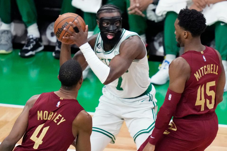 Boston Celtics guard Jaylen Brown (7) looks to pass while pressured by Cleveland Cavaliers guard Donovan Mitchell (45) and forward Evan Mobley (4) during the first half of an NBA basketball game Wednesday, March 1, 2023, in Boston. (AP Photo/Charles Krupa)