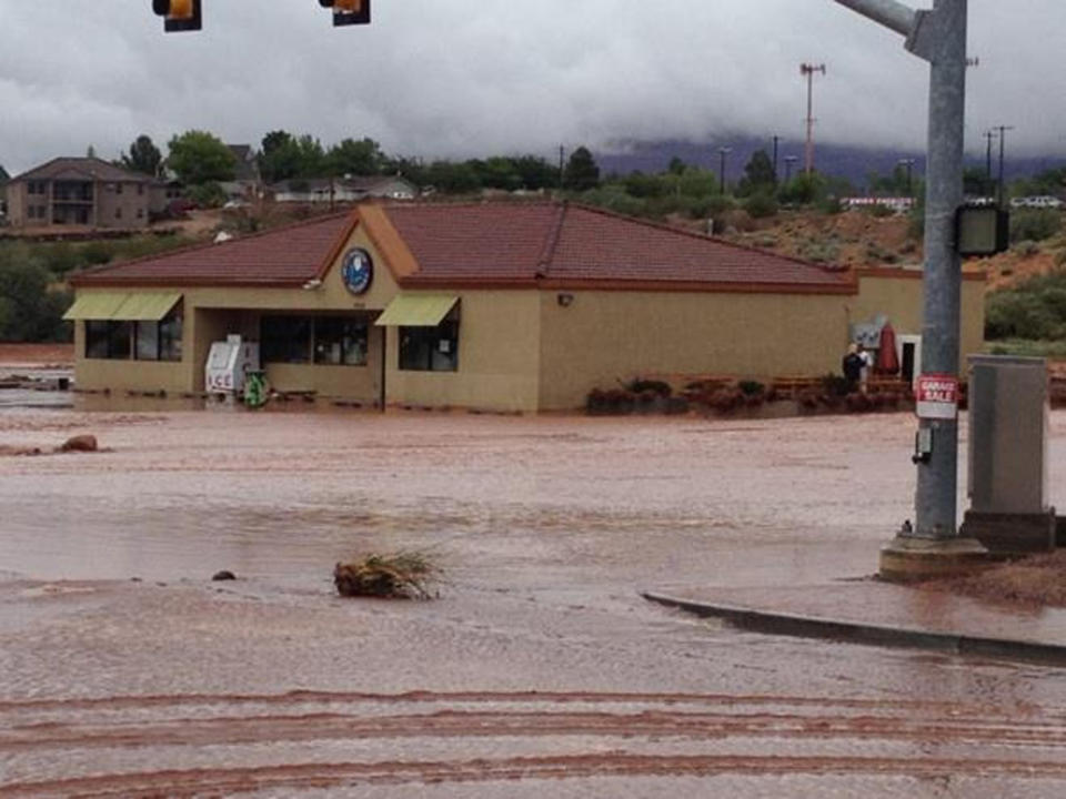 This photo released by the St. George Police Department shows a flooded street after a dike broke and sent floodwaters through the town of Santa Clara, Utah, Tuesday, Sept. 11, 2012. Officials in Santa Clara say they're inspecting whether people can return to about 60 homes and 15 businesses that were evacuated after a dike broke and sent floodwaters through town. City Parks and Recreation Director Brad Hays said a retention pond fed by the Tuacahn Wash filled up after heavy rains Tuesday morning. Authorities ordered homes and businesses below the pond to evacuate about noon, and the dike broke about 45 minutes later. No injuries have been reported from the flooding. (AP Photo/St. George Police Department)
