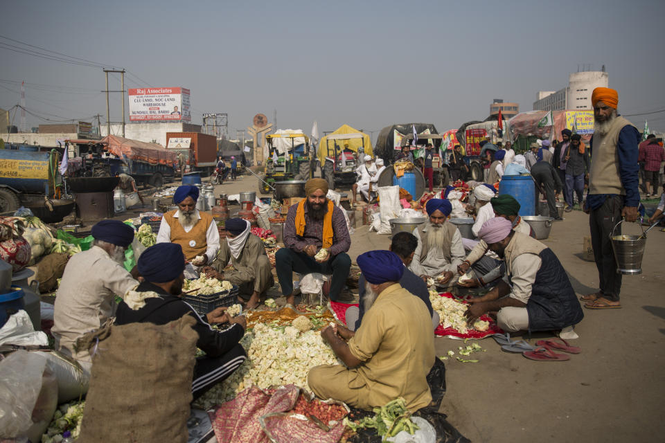 Protesting farmers prepare a meal for fellow farmers as they block a major highway during a protest to abolish new farming laws they say will result in exploitation by corporations, eventually rendering them landless, at the Delhi-Haryana state border, India, Tuesday, Dec. 1, 2020. The busy, nonstop, arterial highways that connect most northern Indian towns to this city of 29 million people, now beat to the rhythm of never-heard-before cries of "Inquilab Zindabad" ("Long live the revolution"). Tens and thousands of farmers, with colorful distinctive turbans and long, flowing beards, have descended upon its borders where they commandeer wide swathes of roads. (AP Photo/Altaf Qadri)