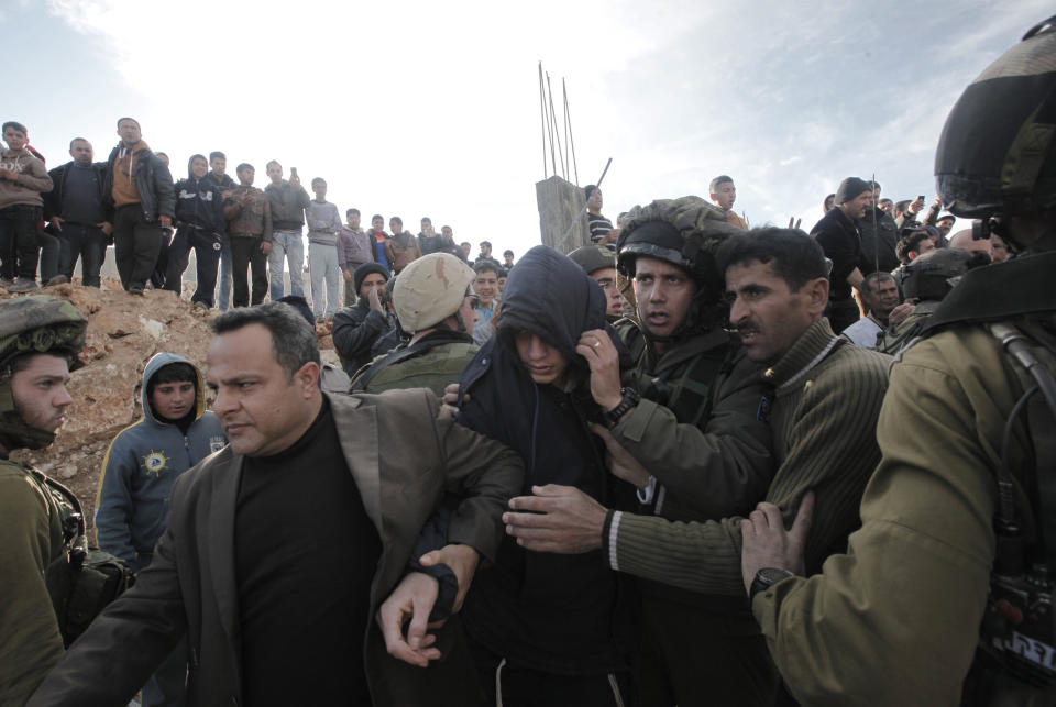 Israeli soldiers and two Palestinians help to evacuate an Israeli settler (C) after he was detained and beaten with his comrades by Palestinians from the West Bank village of Qusra on January 7, 2014. (JAAFAR ASHTIYEH/AFP/Getty Images)