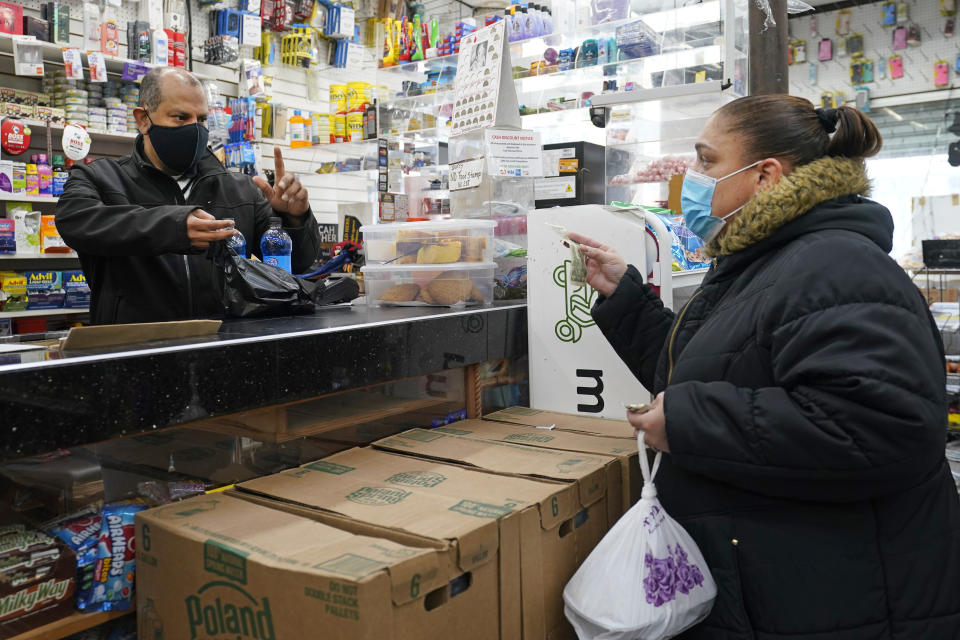 Francisco Marte asiste a una clienta en su bodega del Bronx, Nueva York, el 19 de febrero del 2021. Marte, presidente de una agrupación que nuclea a tiendas de comestibles de Nueva York (el Bodega and Small Business Group), dice que ha hecho gestiones para que las autoridades vacunen a los empleados de ese sector, muchos de los cuales no saben que ya pueden sacar turno para ser inoculados en Nueva York. (AP Photo/Kathy Willens)