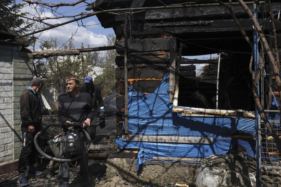 Anwohner stehen neben einem Haus, das bei einem Beschuss beschädigt wurde. (Foto: Andriy Andriyenko/AP/dpa)