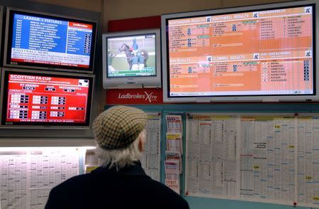 A man watches television screens in a Ladbrokes bookmaker in London February 19, 2009. REUTERS/Luke MacGregor