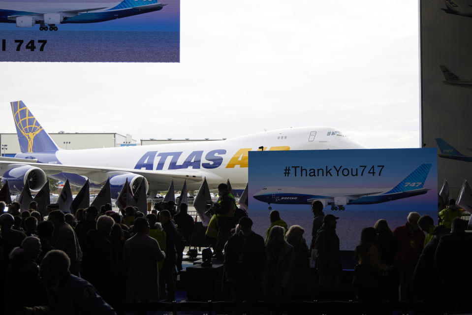 The final Boeing 747 jumbo jet is visible behind a a large screen as the doors of the assembly plant open during a ceremony for delivery, Tuesday, Jan. 31, 2023, in Everett, Wash. Since it debuted in 1969, the 747 has served as a cargo plane, a commercial aircraft capable of carrying nearly 500 passengers, and the Air Force One presidential aircraft. (AP Photo/John Froschauer)