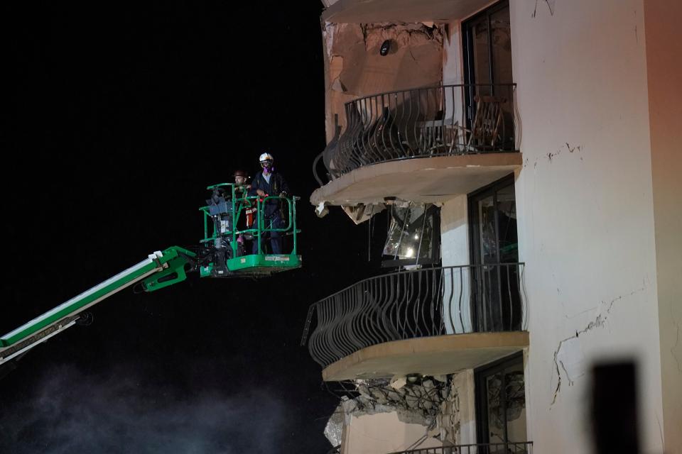 Workers use a lift to investigate balconies in the still-standing portion of the building, as rescue efforts continue where a wing of a 12-story beachfront condo building collapsed (AP)