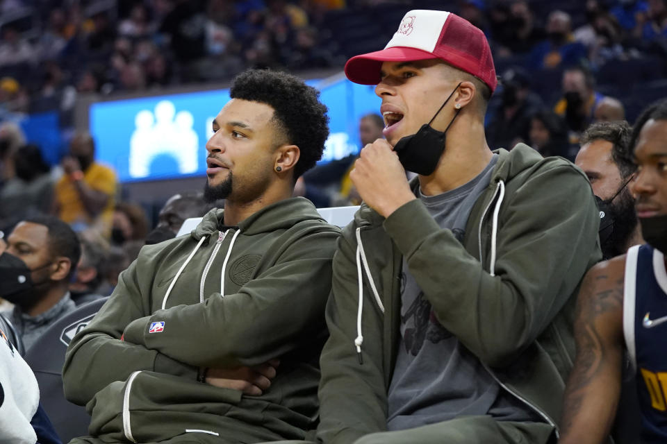 Denver Nuggets' Jamal Murray, left, and Michael Porter Jr. watch from the bench during the first half of the team's preseason NBA basketball game against the Golden State Warriors in San Francisco, Wednesday, Oct. 6, 2021. (AP Photo/Jeff Chiu)