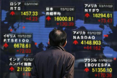 A pedestrian looks at an electronic board displaying various countries' stock market indices outside a brokerage in Tokyo December 24, 2013. REUTERS/Yuya Shino