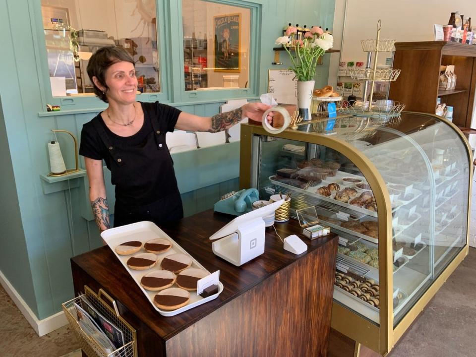 Ivy and the Poet owner Shawn Bakery holds a tray of black and white cookies.