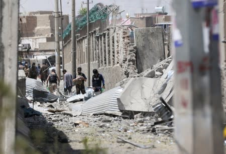 Members of Afghan security forces inspect the site of a car bomb blast in Kabul